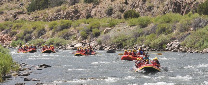 vendégek tutajon navigálás zuhatag hegyek a háttérben az Arkansas river Raft Masters Tours Colorado