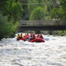 guests in rafts going down Clear Creek with a bridge in background Raft Masters Tours Colorado