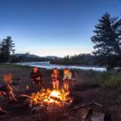 campfire at dusk next to river