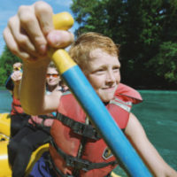 Boy (8-10) with paddle, river rafting with family