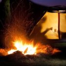campfire at night with tent in background